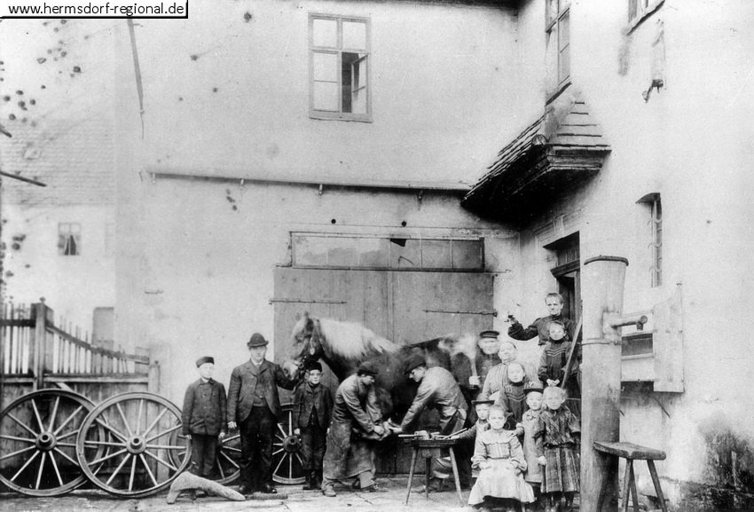 Das Foto aus dem Jahr 1895 zeigt den Holzwarenhändler Friedrich Traugott Plötner (hält das Pferd am Zaum), beim Schmied Traugott Steingrüber (rechts) und sein Sohn Louis.